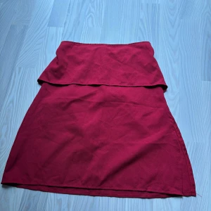 Röd A-linjeformad kjol med volang - Säljer en röd kjol med volangdetalj upptill. Kjolen går att använda som en superfin topp, tyvärr finns det ingen lapp kvar i kjolen så jag vet ej märke eller storlek, men den passar bra som både topp och kjol på mig som har storlek S, skick är supersvår att sätta då alla tycker olika men enligt mig är de ett bra skick på kjolen 