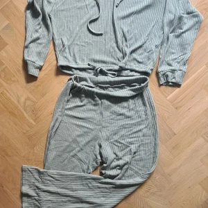 Ribbad grön hoodie set från Gina Tricot - Ribbad hoodie set i ljusgrönt från Gina Tricot. Tröjan har huva med snörning, långa ärmar och byxorna har resår i midjan och är stretchiga