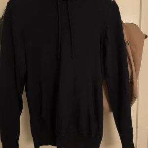 Merino hoodie J.Lindeberg - Snygg och exklusiv mörkblå hoodie i 100% merinoull från J.Lindeberg. Mjuk, lätt och andas bra – perfekt både för vardag och lager-på-lager-look. Huvan är justerbar och plagget har klassiska detaljer som ribbade muddar och avslut. I mycket gott skick, knappt använd. Tröjan är officiellt s men passar xs 