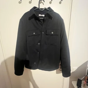 Svart overshirt från Zara, storlek S - Stilren mörk blå overshirt från Zara i storlek S. Jackan har klassisk krage, två stora bröstfickor med knappar och knäppning framtill. Perfekt för lager-på-lager och enkel att matcha till olika outfits.