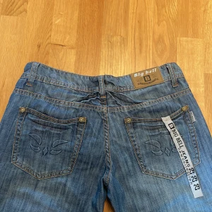 Lowwaisted jeans - Säljer ett par blå jeans från Big Bell med snygg passform. Jeansen har klassiska fem fickor, snygga detaljer på bakfickorna och guldiga nitar. Materialet är jeans med en lätt tvättad look och kontrastsömmar. Perfekta för dig som gillar en retro/vintage vibe.