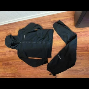 Svarta mjukisbyxor från McKenzie XL - Svarta mjukisbyxor från McKenzie i storlek XL för tonåringar. Byxorna har resår och snörning i midjan samt ribbade muddar vid bensluten. Tillverkade i mjukt bomullsmaterial med diskret McKenzie-logga på benet.