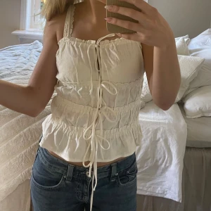 Vit linnetopp - Säljer en söt vit linnetopp med smockade partier och dekorativ snörning framtill. I nyskick 