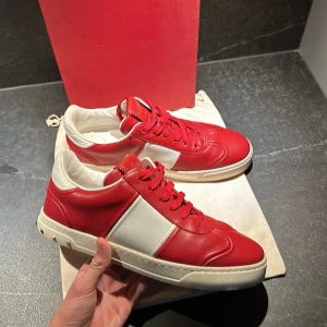 Valentino Garavani röda och vita sneakers - Hejsan! Jag säljer nu dessa riktigt feta skor ifrån valentino flycru i storlek 41-42. Dem är i extremt bra skick och är använda 1-3 ggr. Allt og kommer med vid köp! Hör av er om ni har några frågor!😊