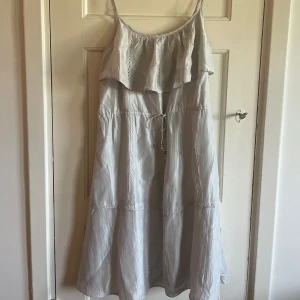 Ljus sommarklänning med volang - Superfin ljus klänning med tunna axelband och volang upptill. Klänningen är perfekt till sommaren.
