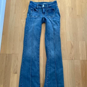 Blå bootcut jeans från Nelly, stl 34 - Snygga blå bootcut jeans från Nelly med låg midja och markerade sömmar framtill. Storlek 34 men sitter som 32 enligt mig då jag inte får på mig dom över höfterna. Lite långa i benen (jag är 161cm), knappt använda då de blev för små :( köpta i vintras för 699 kr. 