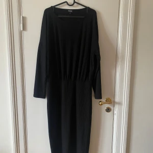 Svart ribbad långklänning Bubbleroom - Svart långklänning från Bubbleroom i storlek XL. Klänningen har ribbad struktur, lång ärm och pass form som är tajtare nertill och lite större på ovandelen.