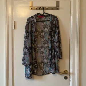 Mönstrad blus från Boohoo i storlek L - Säljer en luftig kimono från Boohoo med. Blusen har långa ärmar och är tillverkad i ett tunt, transparent material som är perfekt att slänga över ett linne.
