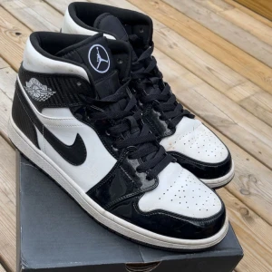 Jordan 1 Carbon fiber mid - Säljer ett par Nike Air Jordan 1 mid sneakers i svart och vitt med klassisk hög siluett. Skorna har svarta snören, svart Swoosh och detaljer i blankt syntetmaterial samt kolfibermönstrade partier. Ikonisk Air Jordan-logga på sidan och Jumpman på plösen. Tvättas såklart innan utskick och box följer med