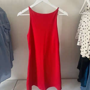 Röd ärmlös klänning Forever 21 S - En snygg röd kortklänning från Forever 21 i storlek S. Klänningen är ärmlös med hög halsringning och rak passform. Perfekt för dig som gillar enkel men stilren design. Tillverkad i ett mjukt och lätt material som känns skönt mot huden.