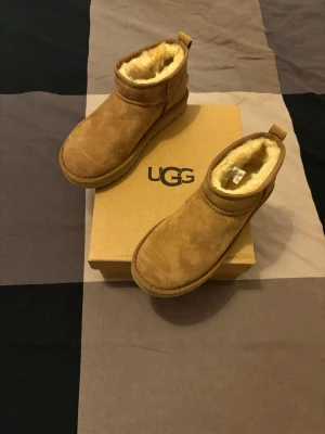UGG Classic ultra mini - Säljer ett par klassiska bruna UGG boots i mjuk mocka med fluffigt foder. Skorna har rund tå, platt sula och dragflik bak. Perfekta för kalla dagar och riktigt sköna att ha på sig. Kommer i originalkartong.