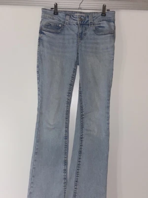 Ljusblå bootcut jeans med fickdetalj - Säljer ett par ljusblå bootcut jeans med snygg tvätt och cool ficka med knapp bak. 