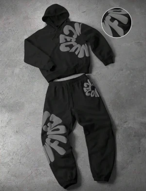 Blomster Hoddie - Säljer en svart väst med stora gråa grafiska bokstäver som ger en cool streetwear-vibe. Hoodien har en avslappnad passform och är tillverkad i mjukt material som känns skönt mot huden. Perfekt för dig som vill sticka ut med en unik look.