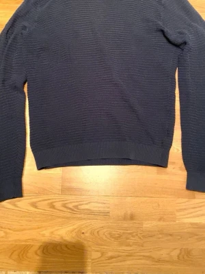 Mörkblå ribbad tröja Dressmann M - Säljer en mörkblå ribbad tröja från Dressmann i storlek M. Tröjan har långärmad passform och är tillverkad i ett mjukt material med diskreta horisontella ränder. Perfekt för dig som gillar enkel och stilren look. Kom görna med prisförslag