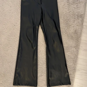 Svarta bootcut byxor i skinn/läder - Säljer ett par svarta bootcut byxor från Madlady i skinn/läder i storlek S. Jätte fint skick och inga tecken på användning
