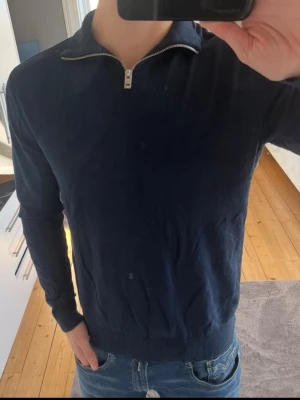 Mörkblå tröja med half zip - Mörkblå Halfzip från Jack and Jones i stl M. Tröjan passar bra på de som brukar ha medium, orginalpris 499. Använts 3-5 gånger, alltså bara tagit plats i garderoben. Underarmarna töjs lätt ut om man drar upp ärmarna, men de återställs efter en tvätt igen - men därav det billiga priset. 