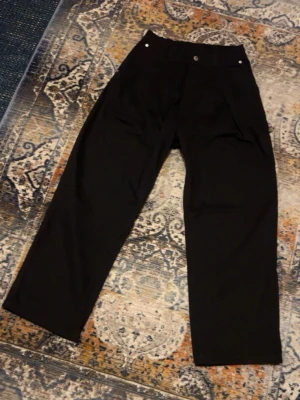 Svarta wide byxor från District Fortysix - Säljer ett par svarta byxor från District Fortysix i storlek XS. Byxorna har bred passform, resår i midjan och en broderad logga bak. Tillverkade i ett mjukt bomullsmaterial och har raka ben för en chill look.