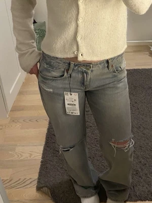 Levis 501 ljusgrå slitna jeans - Säljer ett par jeans i ljusgrå tvätt med slitningar och hål på knäna för en riktigt avslappnad vibe. Klassisk femficksmodell med raka ben och låg midja. Perfekta till sneakers och en enkel topp. Zara jeans.💕💕