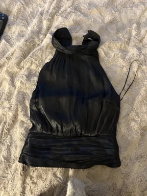 Svart halterneck topp Gina Tricot - Svart fest topp eller likande har bara använt en gång, materialet är lite silkes så färgen sviftar lite 