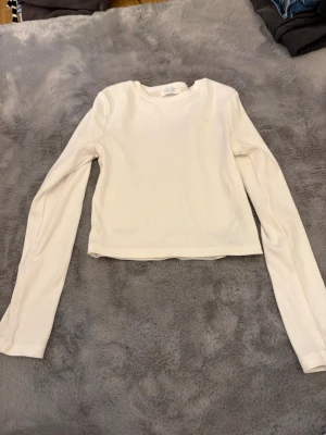 Vit ribbad långärmad topp Primark - En enkel och stilren vit långärmad topp från Primark. Toppen är ribbad och har en klassisk rund halsringning. Perfekt att matcha med jeans eller kjol för en clean look.