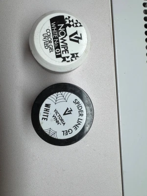 Victoria Vynn vita nagelgeler. Båda 140kr - Två burkar nagelgel från Victoria Vynn: en No Wipe Color Gel White No. 01 för UV/LED och en Spider Line Gel White. Båda är vita och kommer i runda plastburkar, perfekta för kreativa nageldesigner och detaljerade linjer.