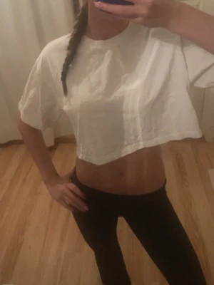 Vit croppad topp från Gina Tricot - Säljer en vit croppad topp från Gina Tricot, basically basics-kollektionen. T-shirten har lös passform, korta ärmar och är tillverkad i mjuk bomull. Perfekt till jeans eller kjol för en chill look.