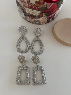 Glittriga silvervästar med paljetter oanvända  - Säljer två olika glittriga silvervästar, en med droppformad design och en med rektangulär form. Båda är täckta av paljetter som ger en riktigt festlig vibe. Perfekt för dig som vill sticka ut och addera extra bling till outfiten.