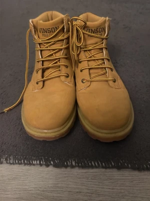 Beiga boots från Vinson Polo Club - Säljer ett par klassiska beiga boots från Vinson Polo Club med snörning och robust sula. Skorna är i skinn och har en rund tå. Perfekta för höst och vinter när du vill ha en stilren och tålig look.