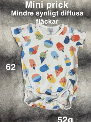 Färgglad glassmönstrad body Polarn O. Pyret - Söt body från Polarn O. Pyret i storlek 62 med korta ärmar och ett lekfullt mönster av glassar och strutar i blått, rött, gult, grönt och orange. 🌸 Mini prick sant några väldigt diffusa och svaga fläckar. Ej använd många gånger. Storlek 62