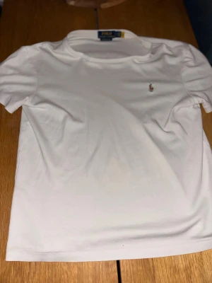 Vit t-shirt från Polo Ralph Lauren - Säljer en vit t-shirt från Polo Ralph Lauren med klassisk broderad logga på bröstet. Modellen är custom slim fit och har korta ärmar. Kom med pris!