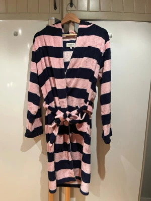 Morgonrock - Sparsamt använd morgonrock i storlek 170. Hel och ren, rök och djurfritt hem. Rosa och mörkblå randig. Säljes då den inte blir använd. Två fickor fram, mobil får plats men sticker eventuellt upp lite från kanten.