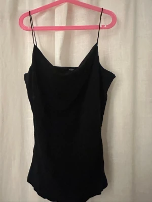 Svart glittrig linnetopp från H&M - Säljer en svart linnetopp från H&M i storlek S. Toppen har tunna axelband och ett glittrigt tyg som ger en snygg effekt. Materialet är mjukt och följsamt, perfekt för dig som gillar stilrena plagg med lite extra shine.