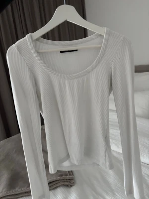 Vit ribbad långärmad topp - Säljer en stilren vit långärmad topp från Bikbok. Toppen är ribbad med rund halsringning och har en slim passform som sitter snyggt på kroppen. Perfekt att matcha med jeans eller kjol för en enkel och fräsch look.
