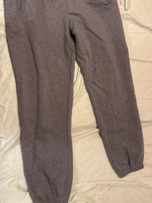 Grå mjukisbyxor från Calvin Klein - Säljer ett par grå mjukisbyxor från Calvin Klein med elastiska muddar vid bensluten och fickor på sidorna. Byxorna har en enkel och clean look med Calvin Klein-logga längs benet. Materialet är mjukt och består av bomull och polyester. Använd ett fåtal gånger. nypris 1200. Xs men sitter som S-M