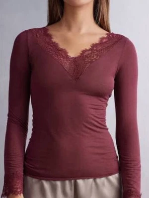 Vinröd långärmad topp med spets - Vinröd långärmad topp med v-ringning och fina spetsdetaljer vid halsringning och ärmslut. Toppens material är mjukt och stretchigt, vilket ger en slim passform. Perfekt för dig som gillar en feminin och stilren look.