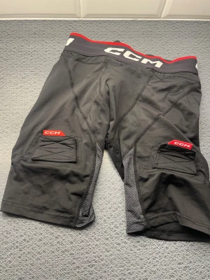 Ccm suspshorts compression - Knappt använda… Svarta träningsshorts från CCM i storlek XL. Shortsen har röda och vita detaljer vid midjan och logga på benen. Tillverkade i ett stretchigt syntetmaterial med förstärkta sömmar och praktiska fickor på sidorna. Perfekta för sport och aktivitet. 