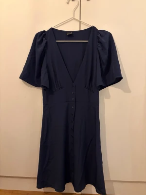 Gina Tricot  - Medellång V-ringad klänning med knappar nerför mitten. Luftig och tunn. 