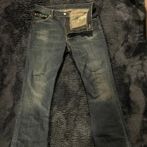 Levi's 507 jeans W33 L32 blå - Säljer ett par Levi's 507 jeans i klassisk blå denim med slitningar vid fickor och kontrastsömmar. Modellen är lagomt bootcut och ger en snygg siluett och passande för en avslappnad ”archive-stil” Köpt här på Plick, för 800kr och de är använda en gång. Bara att kontakta vid funderingar!