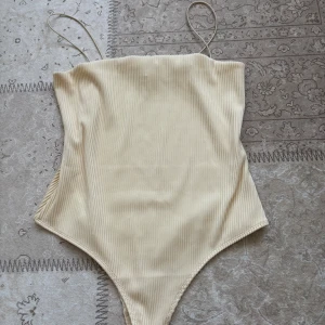 Beige ribbad body från H&M - Säljer en beige body från H&M i storlek M. Modellen har tunna axelband och är ribbad i materialet. Passade ej, köpt nyligen. 