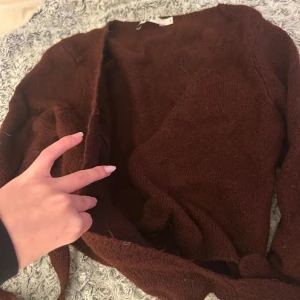 Vinröd omlottkofta från NA-KD - Supermysig vinröd stickad kofta från NA-KD med omlottmodell och långa ärmar. Koftan har ett knytband i midjan som gör att du kan justera passformen. Perfekt för att ge din outfit en chill och snygg vibe.