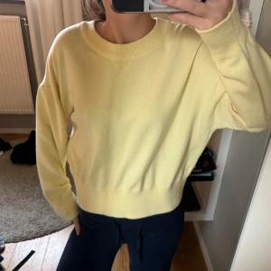 Ljusgul stickad tröja med rund hals - Superfin ljusgul stickad tröja med rundad hals och ribbade muddar vid ärmslut och nederkant. Modellen är loose fit och har långa ärmar. Perfekt för dig som gillar mjuka och sköna plagg i en fräsch färg.