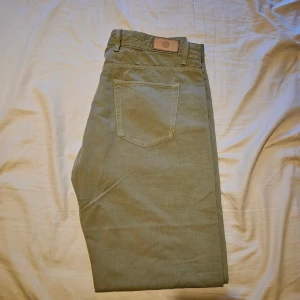 Slim fit chinos från Massimo Dutti - Snygga slim fit chinos från Massimo Dutti i en khaki färg. Klassisk femficksmodell med knapp och dragkedja framtill. Tillverkade i mjuk bomull som ger en skön känsla och stilren look. Perfekta för dig som gillar en smalare passform.