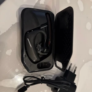Plantronics Bluetooth Headset - Trådlöst Plantronics headset med laddningsfodral och laddare. Perfekt för handsfree-samtal och lång batteritid. Headsetet ser ut att vara i gott skick utan synligt slitage. Levereras komplett med tillbehör.
