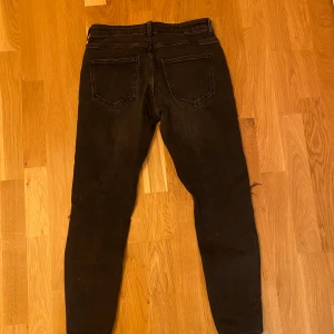 Svarta ripped jeans från Zara, strl 40 - Säljer ett par svarta jeans från Zara i storlek 40 med snygga slitningar och hål på benen för en edgy look. Modellen är slim fit med klassiska fem fickor och knappstängning. Perfekt för dig som gillar streetstyle och vill sticka ut.