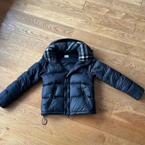 Burberry jacka  - Säljer nu denna jacka från burberry storlek 36. Jag köpte den själv här på plick och den förra ägaren köpte den 2022 ifrån burberrys hemsida. Med tanke på att den är från 2022 är den endå i fint skick. Därimot har den tagit skada i armvecken där den har fått lite mindre vaddning (se bild 4). Det finns kvitto och klarar legit check men jag är endå lite osäker på om den är äkta därav det lägre priset. Skriv om ni har frågor eller är intresserade.