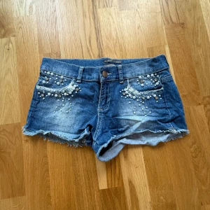Blå jeansshorts med detaljer - Snygga blå lågmidjade jeansshorts från Silvian Heach med fina detaljer