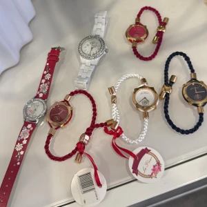 Färgglada klockor från ur och pen  - Säljer flera snygga klockor från ur och pen med olika färger och detaljer. En röd klocka med blommigt mönster och strass, en vit klocka med glittrande ram, samt armbandsklockor med flätade band i rött, vitt och marinblått. Ur med guldfärgade detaljer och stilrena urtavlor.   Styckvis kostar de 65kr och om man köper alla får man de för 350kr. 