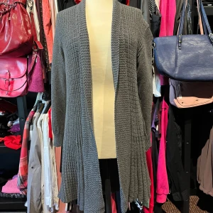 Grå lång kofta från Remel London - Säljer en grå lång kofta från Remel London i stickad bomulls- och akrylblandning. Koftan har öppen front, lång ärm och ett snyggt strukturerat mönster med bred ribbad kant nedtill. 