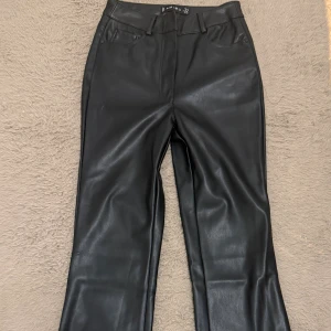 Svarta skinnbyxor från Amisu - PRIS KAN DISKUTERAS - Snygga svarta mid/highwaist skinnbyxor från Amisu i storlek 32. Byxorna har klassisk femficksdesign, bälteshällor och är utsvängda. Materialet är syntetiskt skinn som passar för en ”night out” med ens vänner eller att ha på ett vanligt dag. Perfekt för dig som vill adda lite extra med din outfit. Använt bara en gång under nyårsafton. 