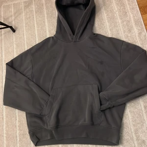 Mörkgrå hoodie Från zara - En stilren mörkgrå hoodie med huva och stor känguruficka framtill. Tröjan har en relaxed passform och är perfekt för chill dagar. Tillverkad i mjukt material som känns skönt mot huden. Långa ärmar och ribbade muddar för extra komfort.